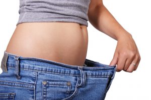 Image of a woman holding loose jeans out